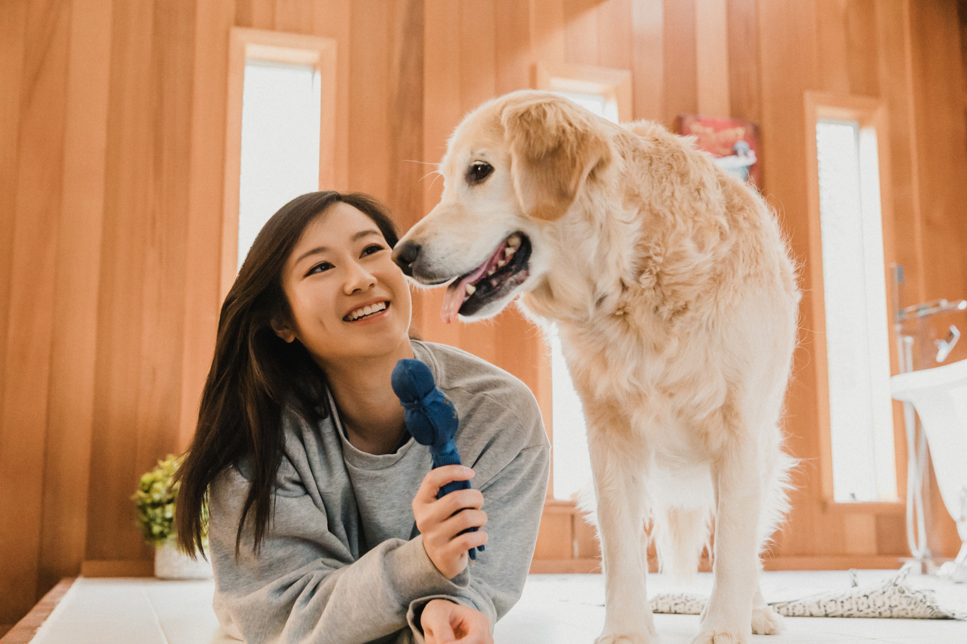 Smiling pet parent bonding with her golden retriever at home